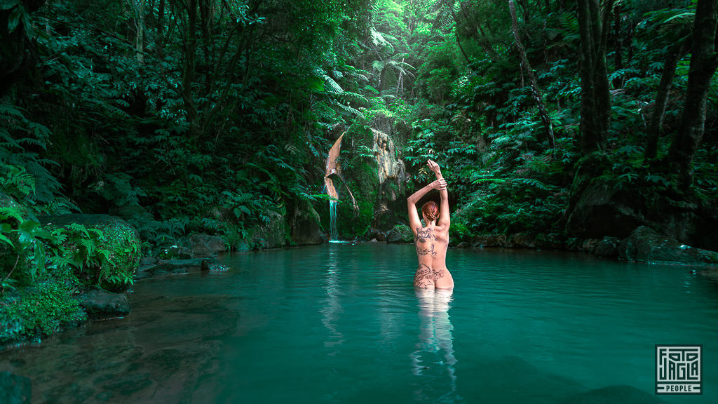 Nackte Frau badet im Naturschwimmbecken mit Wasserfall im Naturdenkmal Caldeira Velha auf der Insel São Miguel auf den Azoren